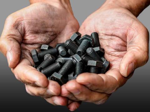 Hands hold black coated nuts and bolts